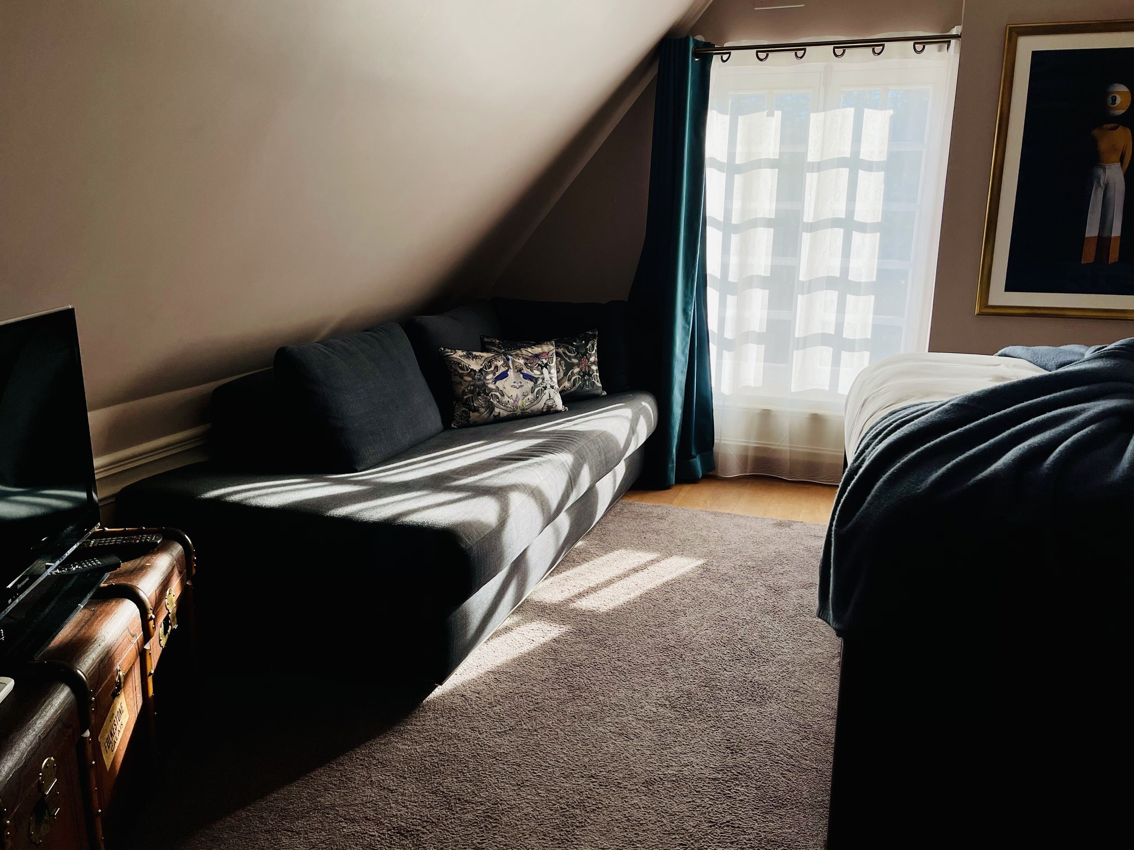 A cozy room with a bed, a sofa, and a desk with a laptop.