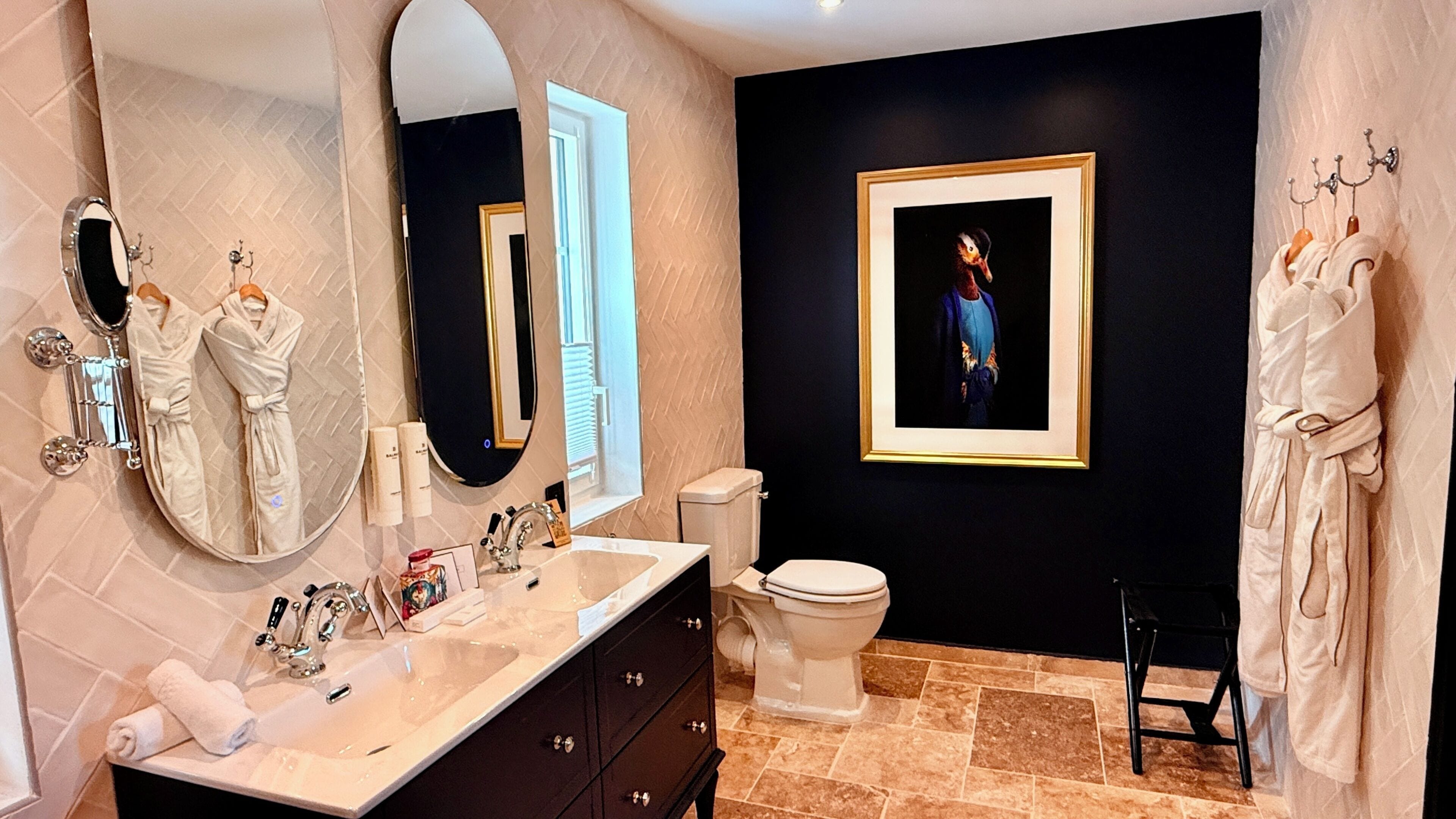 Une salle de bain avec un grand miroir, un lavabo, des toilettes et un tableau encadré au mur.