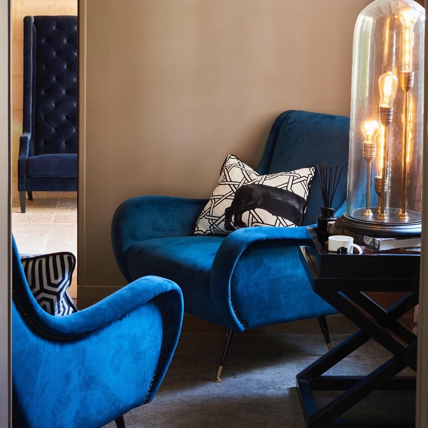 Een kamer met een blauwe fauteuil, een bijpassende bank en een glazen lamp met lichtbollen.