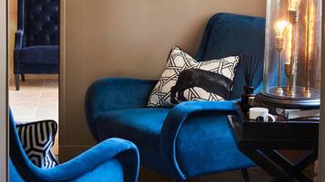 Een kamer met een blauwe fauteuil, een bijpassende bank en een glazen lamp met lichtbollen.