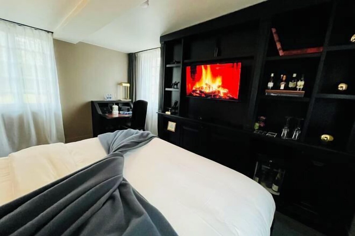 A hotel room with a bed, a television mounted on the wall, and a minibar.