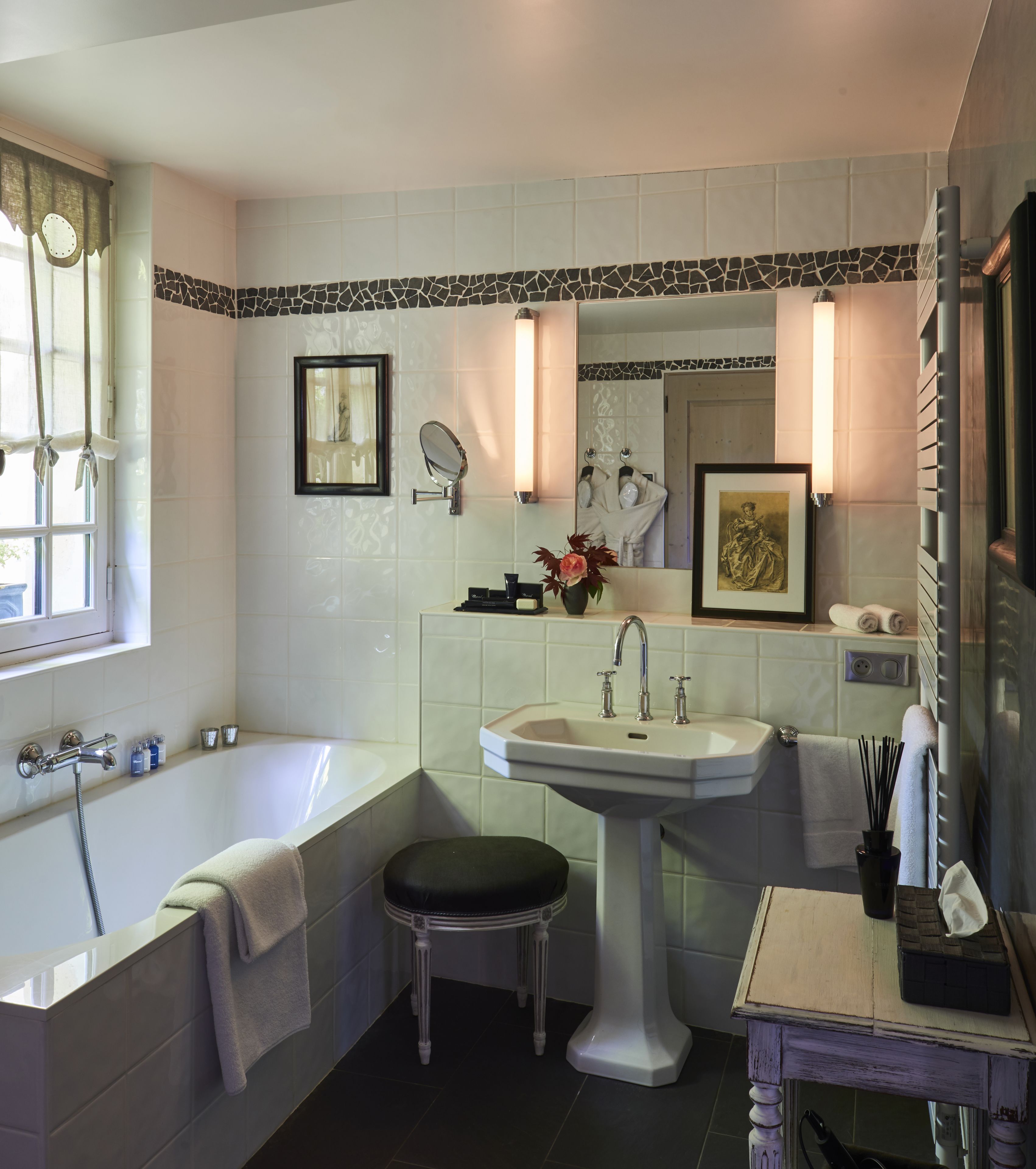 A bathroom with a bathtub, a sink, a mirror, and a vanity.