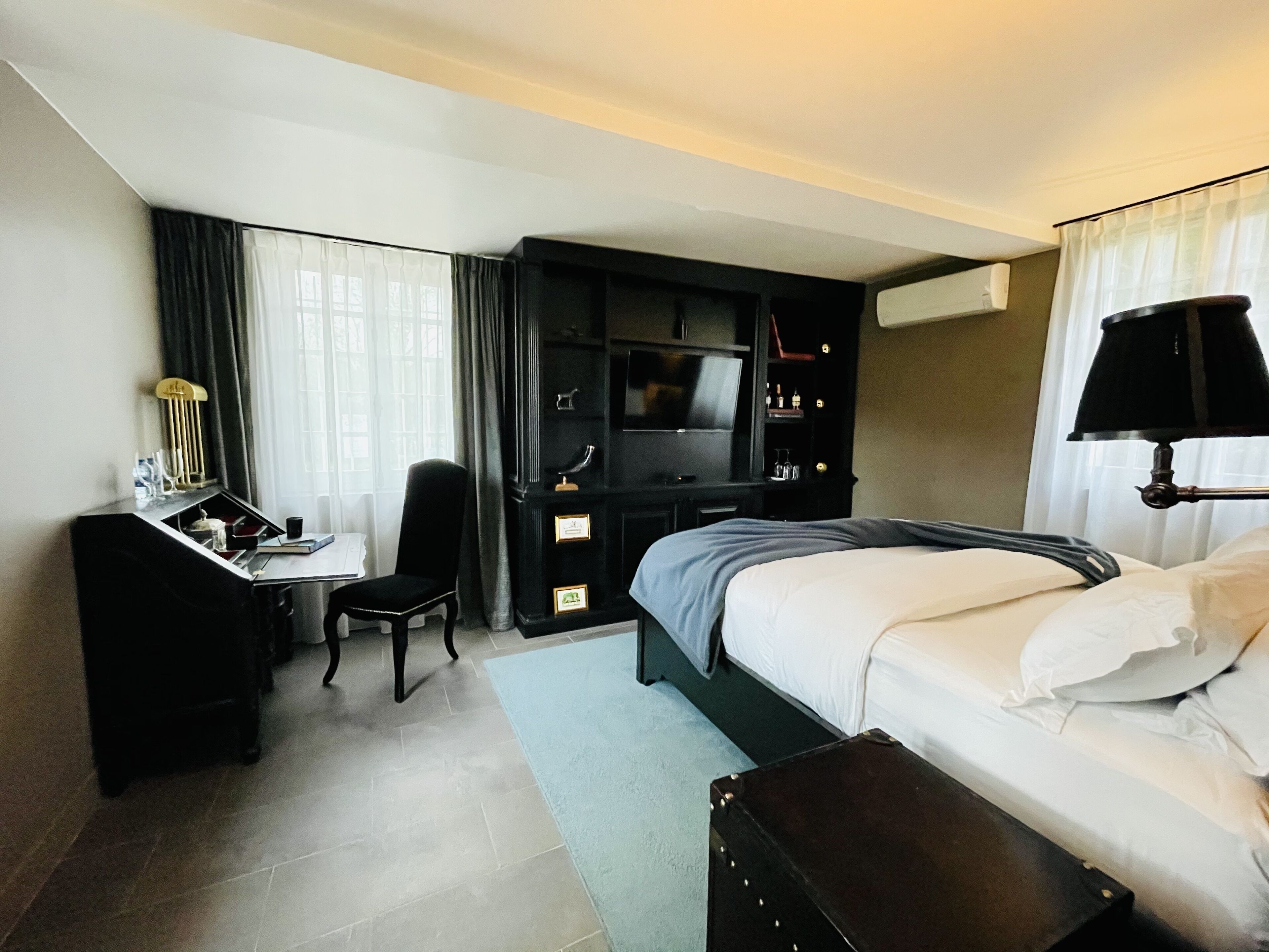 Une chambre d’hôtel comprenant un lit, un bureau avec une chaise, une télévision et une lampe.