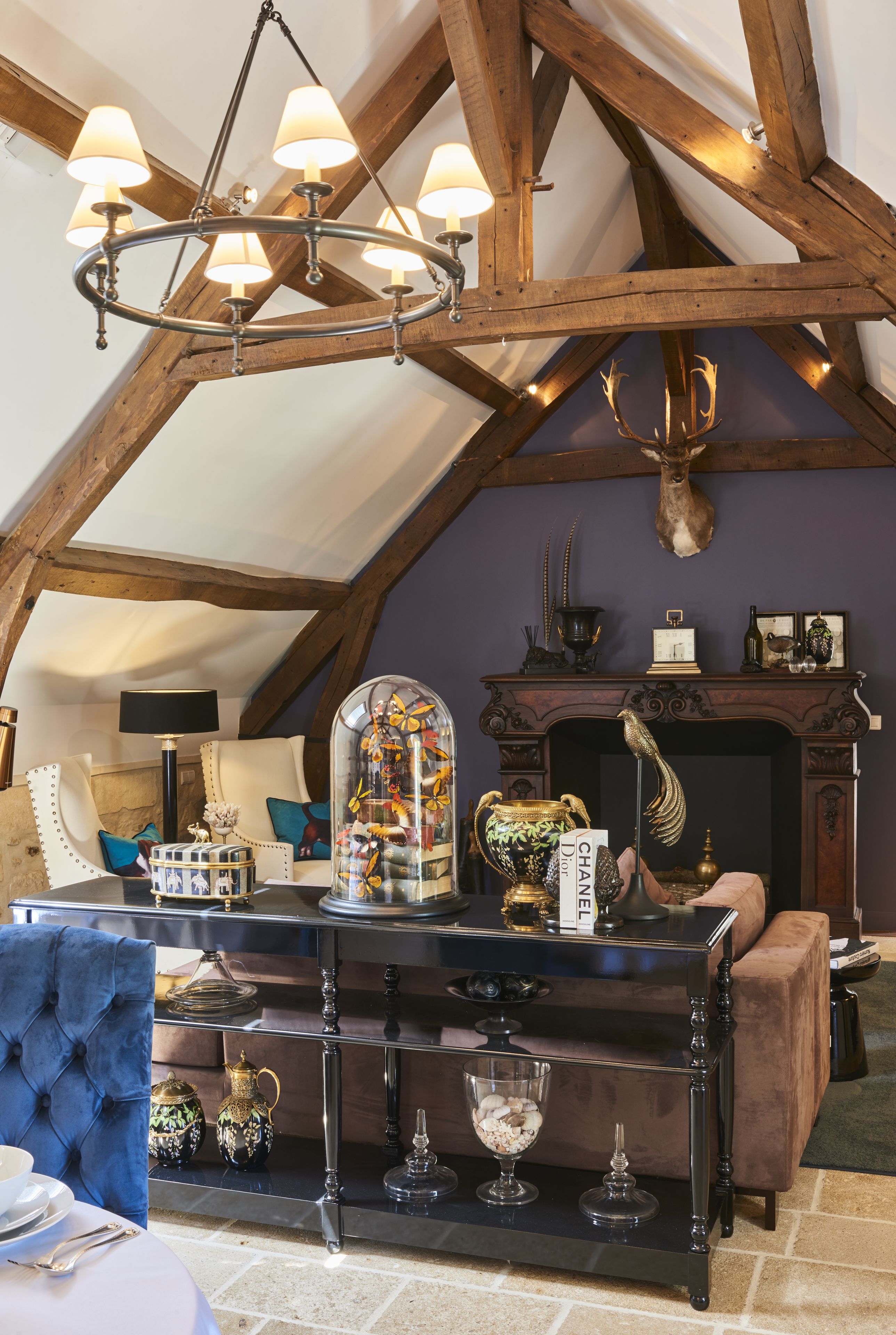 A room with a vaulted ceiling, a chandelier, a fireplace, and a table with various decorative items.