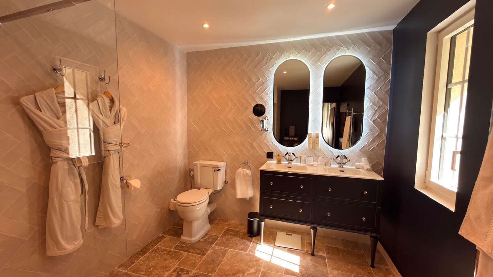 A bathroom with a toilet, a vanity with a mirror, and a robe hanging on the wall.