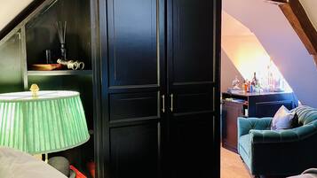 Una habitación con un armario negro, una lámpara verde, un sofá color turquesa y suelo de madera.