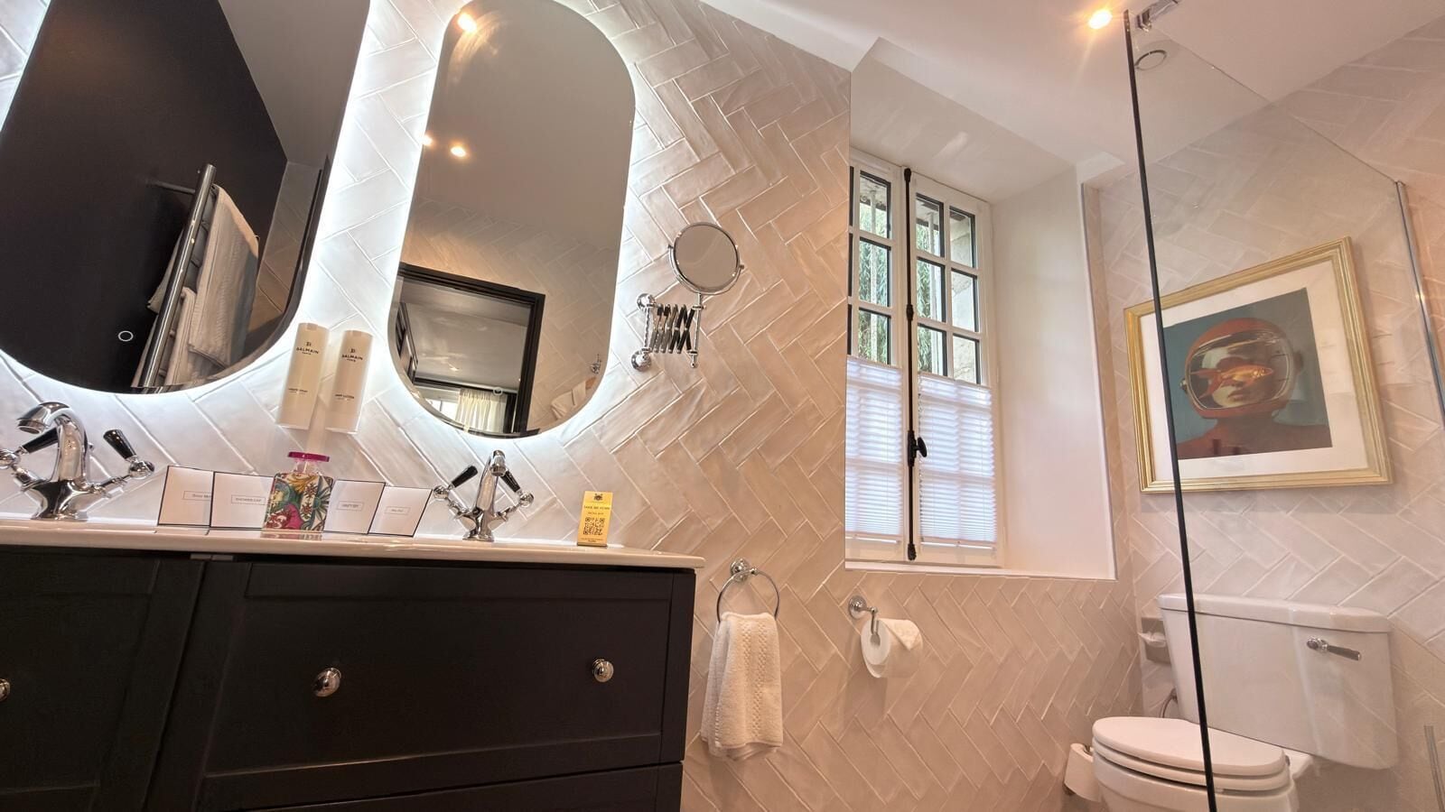Een badkamer met een grote spiegel, een wastafelmeubel met een wastafel, een toilet en een douche.