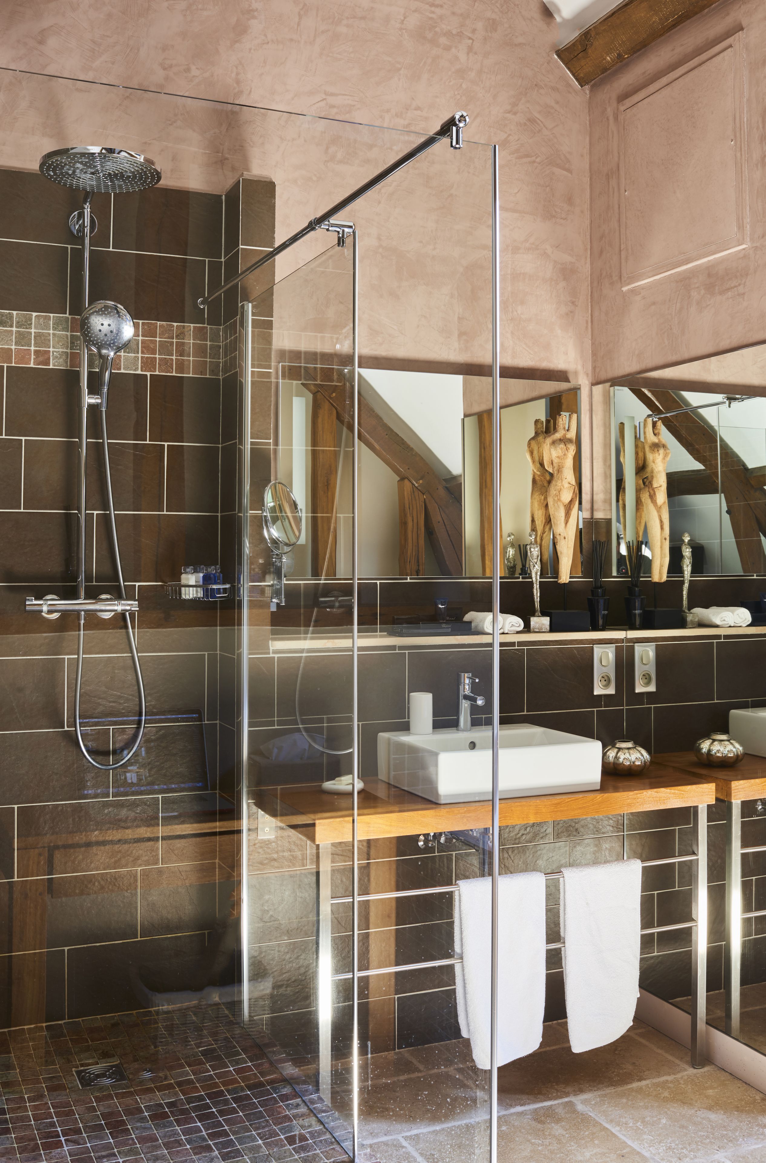 A modern bathroom with a glass-enclosed shower, a large mirror, and a wooden vanity.