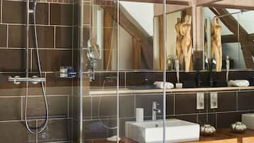 A modern bathroom with a glass-enclosed shower, a large mirror, and a wooden vanity.