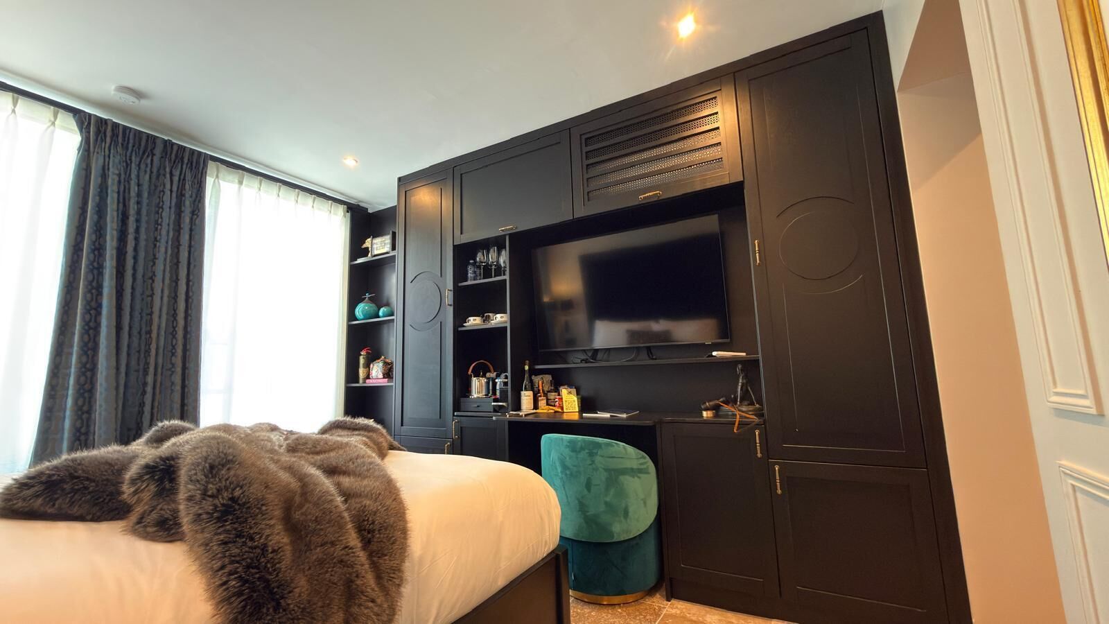 A bedroom with a bed, a TV, a wardrobe, and a desk.