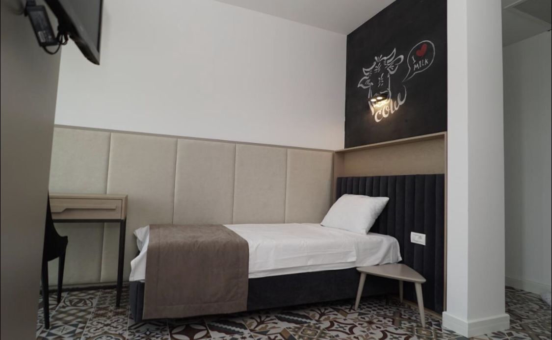 Una habitación de hotel moderna con cama, mesita de noche y una obra de arte colgada en la pared.