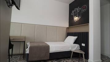 A modern hotel room with a bed, bedside table, and a wall-mounted artwork.
