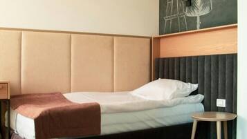 A hotel room with a bed, a small round table, a decorative wall mural, and patterned floor tiles.