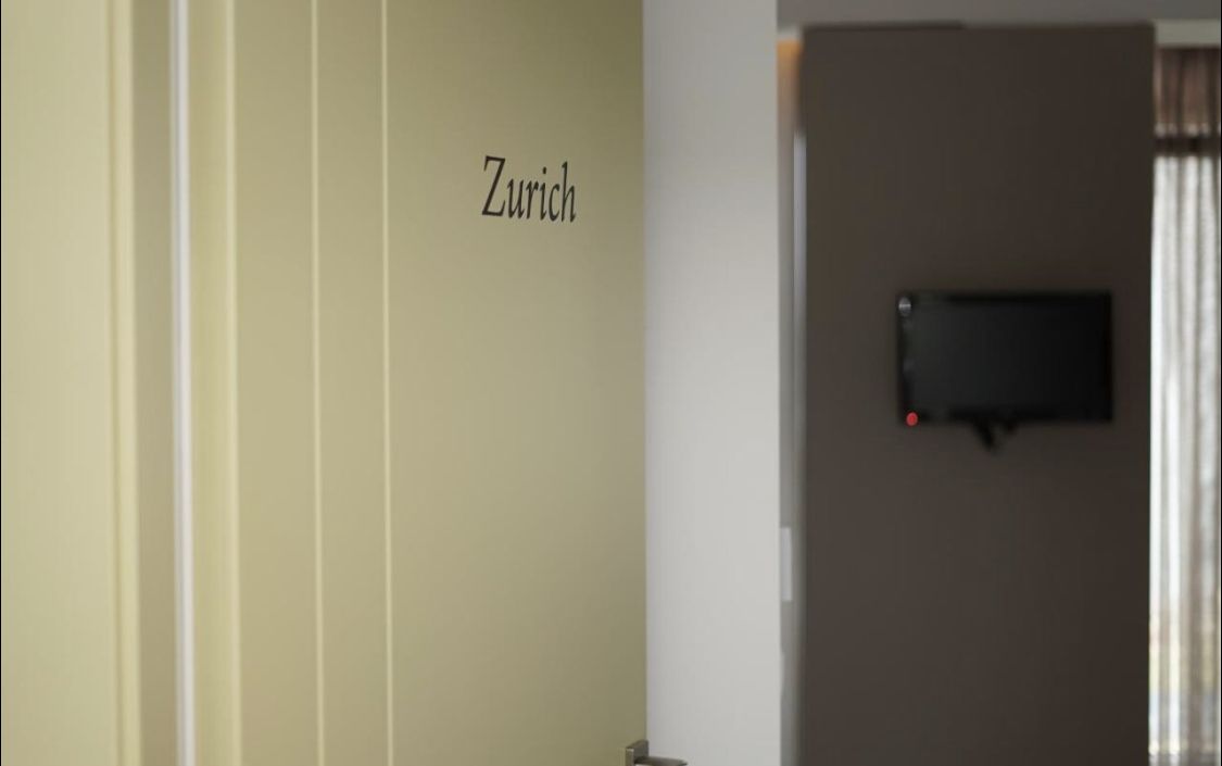 Eine Tür mit einem Schild, auf dem Zürich steht, und eine an der Wand befestigte Überwachungskamera.