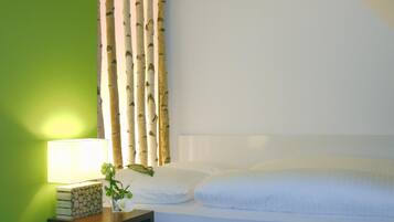 A neatly made bed with white linens, a bedside table with a lamp, and a green wall.