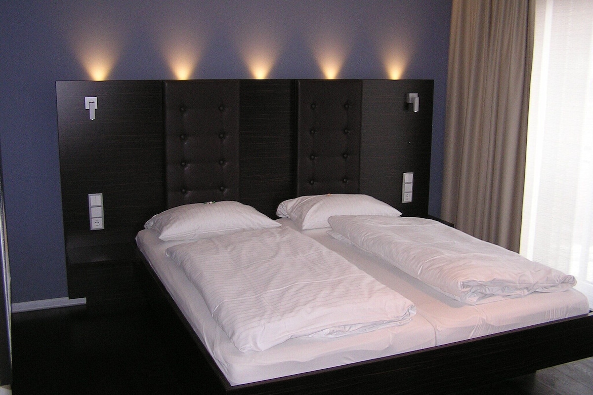 A double bed with a dark headboard and two bedside lamps.