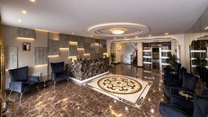 Un hall d’hôtel moderne comprenant un comptoir d’accueil, un espace salon et un escalier menant aux autres étages.