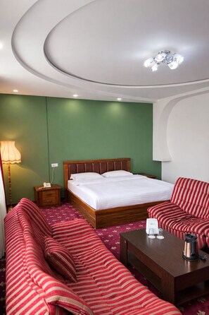 A hotel room with a bed, a sofa, a coffee table, and a lamp. - Gyumri Hotel (Gyumri)