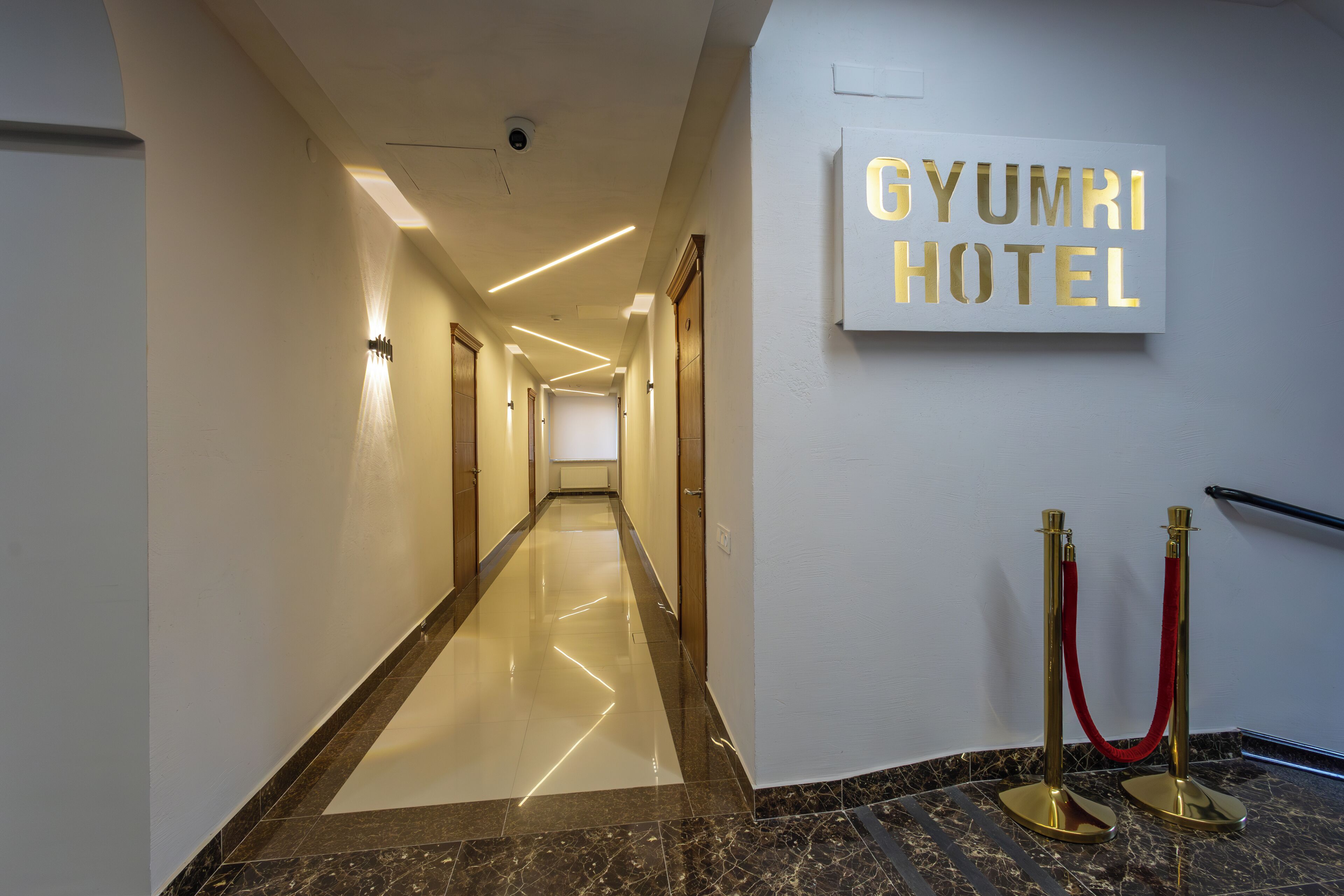 Un pasillo de hotel con piso de mármol pulido, un cartel que dice 