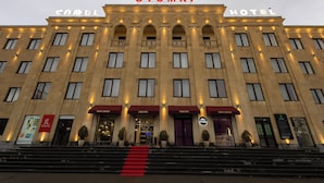 Un hôtel reconnaissable à son grand panneau « GYUMRI », à ses nombreux balcons et à un tapis rouge menant à l’entrée.