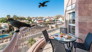 A balcony with a dining table, chairs, and a bird perched on the railing. - Renovated White 3BD next to Beach - Pool (Eilat)