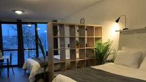 Un dormitorio moderno con una cama grande, una estantería de madera y vista a la calle.
