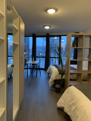 Una habitación de hotel moderna con un ventanal grande, una zona de comedor y una estantería.