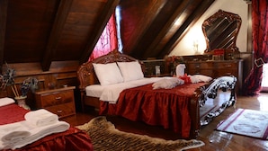 A bedroom with a wooden bed, a red upholstered chair, a large mirror, and a tiger skin rug.