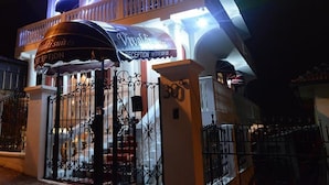 A hotel entrance with a reception area, a balcony, and a gated entrance.