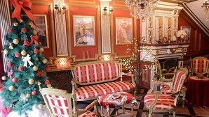 A grand room with ornate furniture, a Christmas tree, and classical paintings.