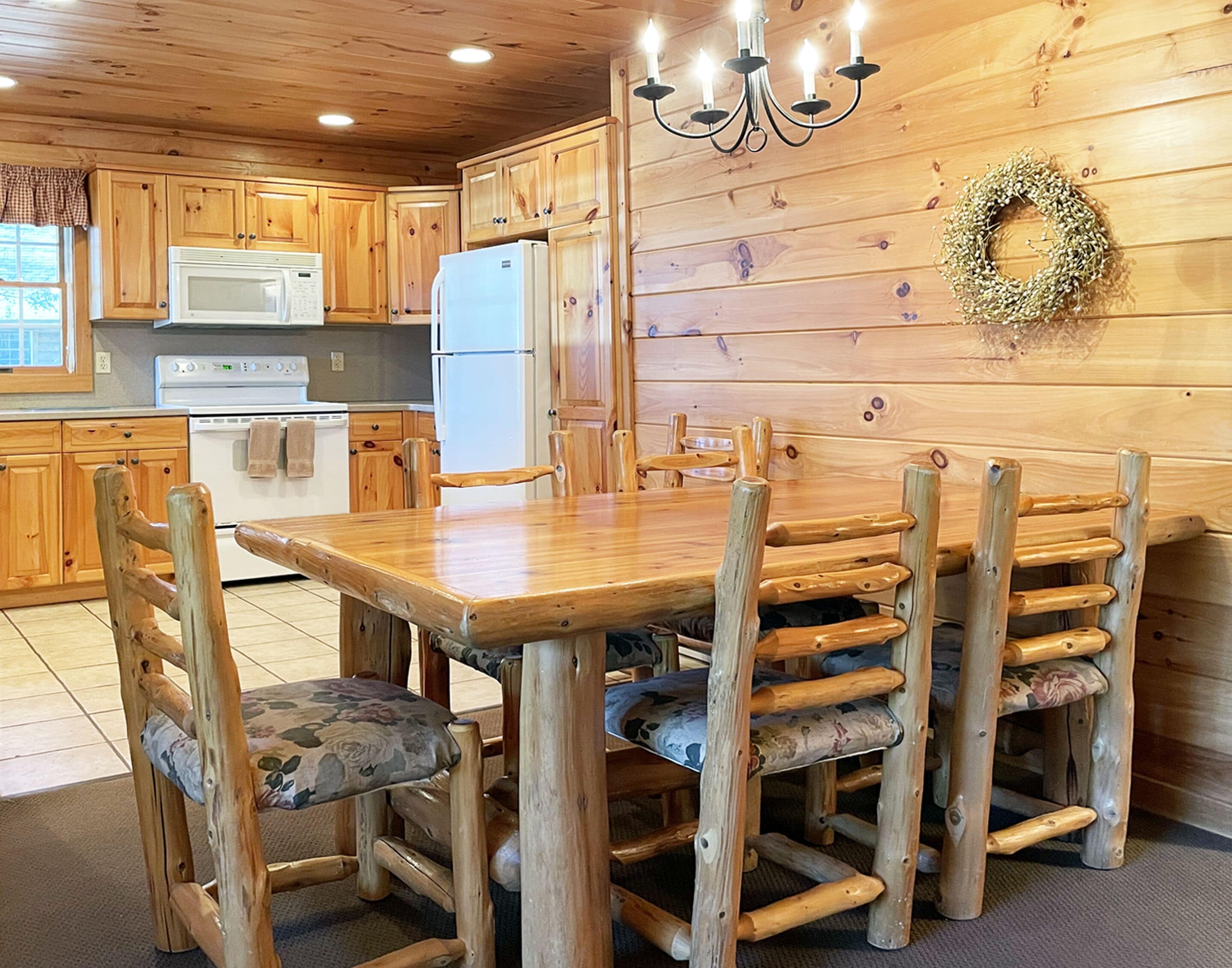 A wooden interior with a dining table and chairs, a refrigerator, and a microwave.