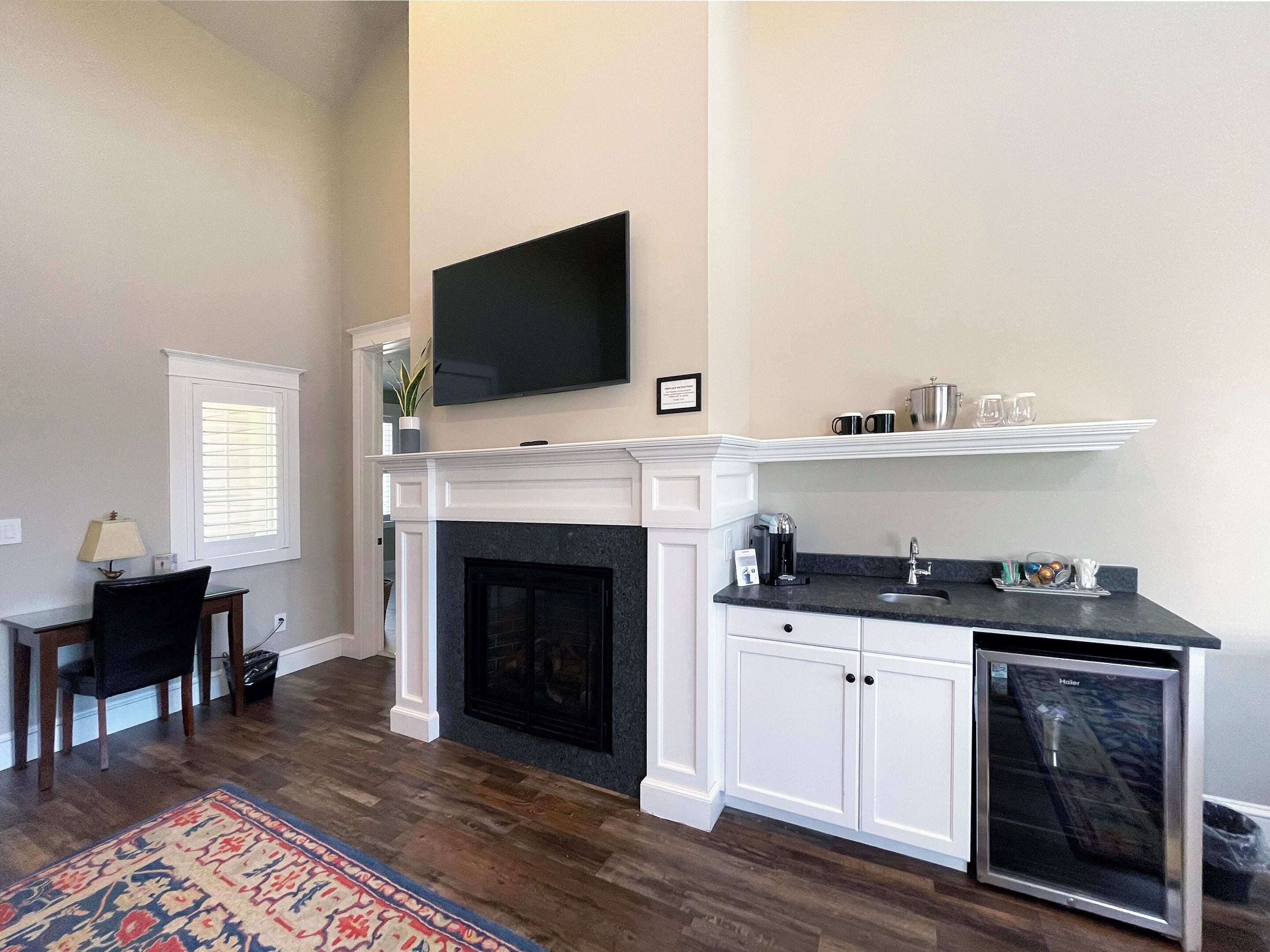 A modern kitchen with a fireplace, a flat-screen TV, and a coffee maker.
