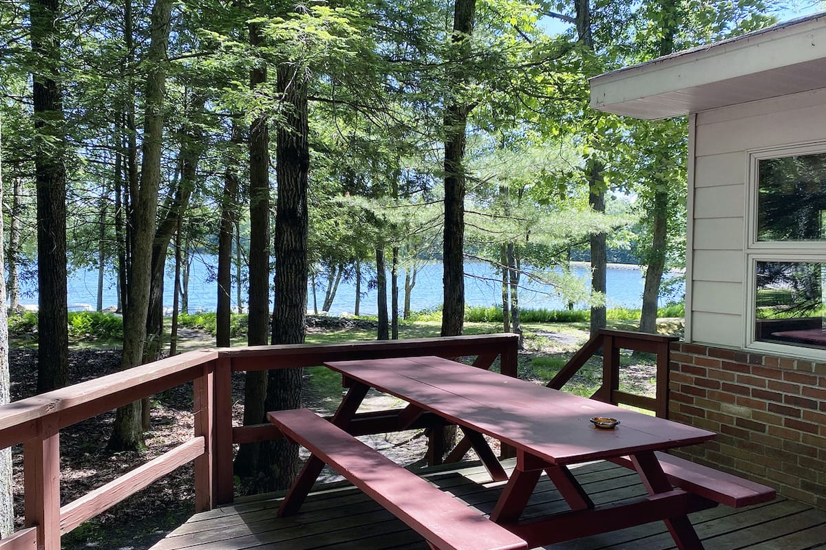A wooden deck with picnic tables overlooking a lake.
