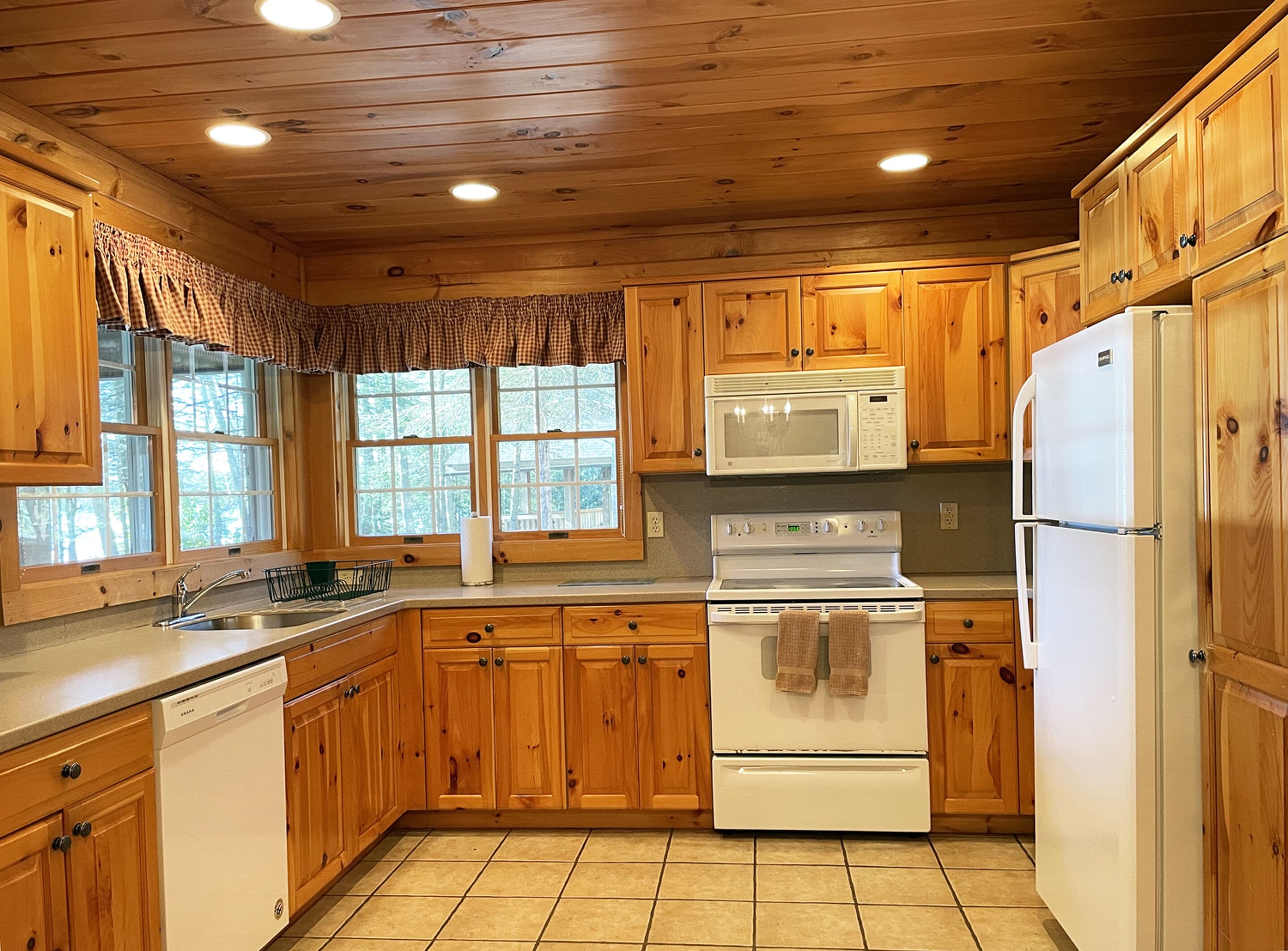 A kitchen with wooden cabinets, a white stove, a microwave, and a refrigerator.