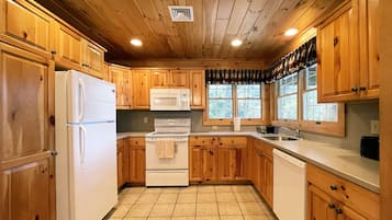 A kitchen with wooden cabinets, a refrigerator, a microwave, a stove, and a sink.