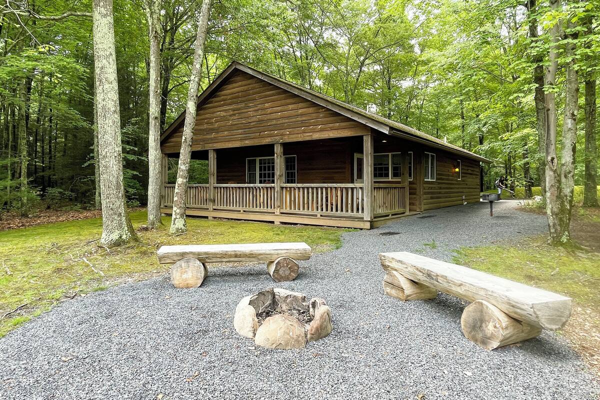 A rustic cabin with a porch, surrounded by trees.