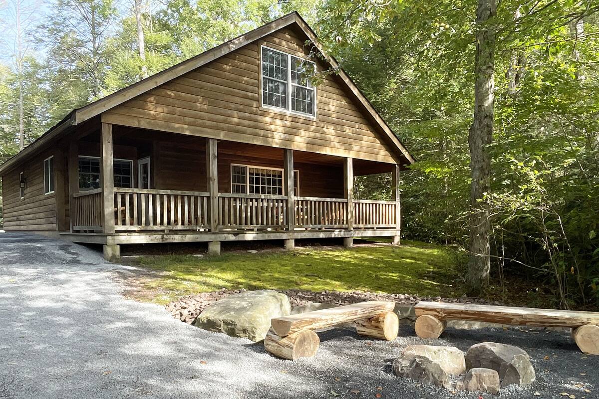 A wooden cabin with a porch and a stone pathway leading to the entrance.