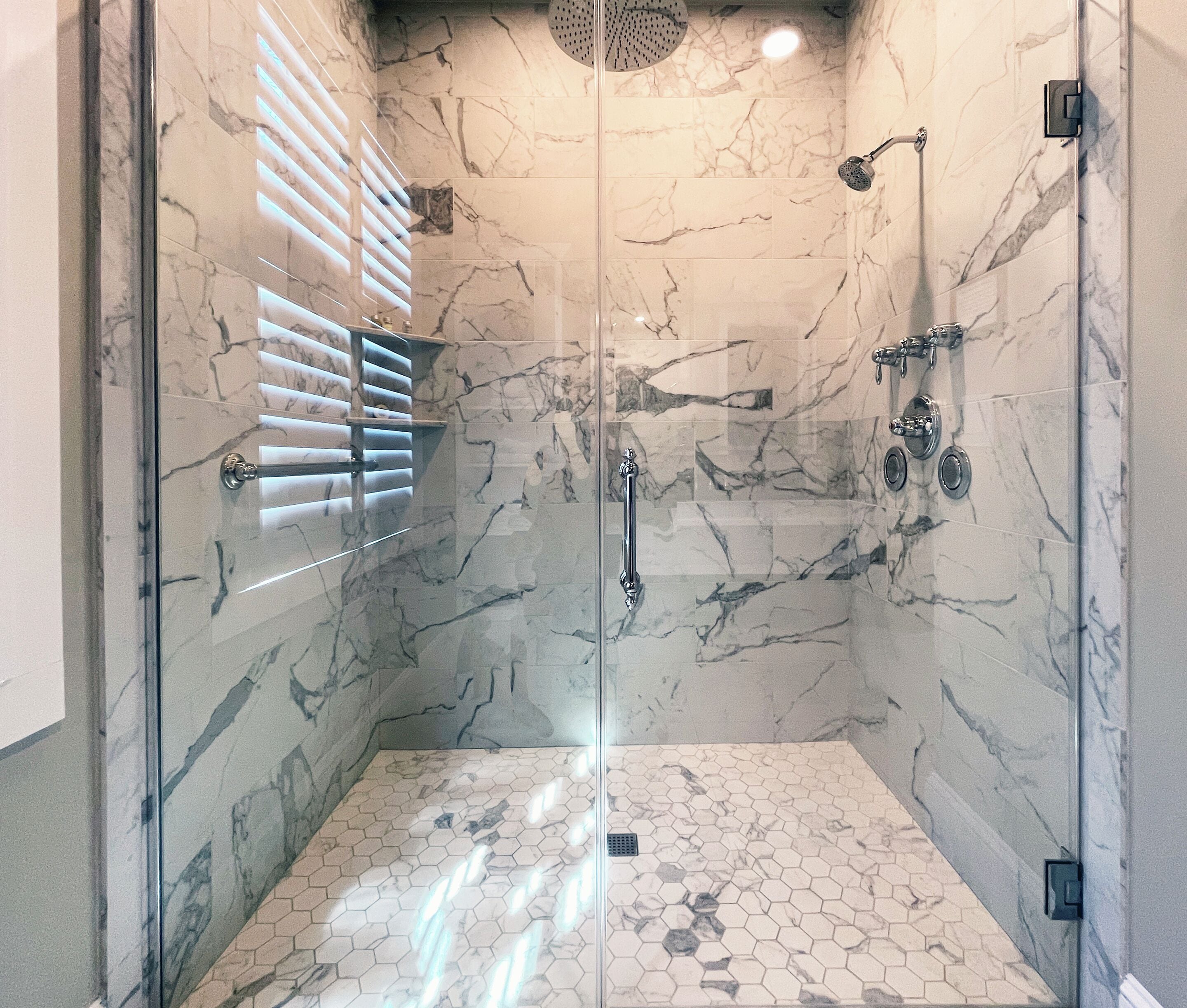 Une douche entièrementClose avec des murs en marbre et un sol carrelé en forme d’hexagone.