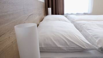 A neatly made bed with white linens and a wooden headboard.