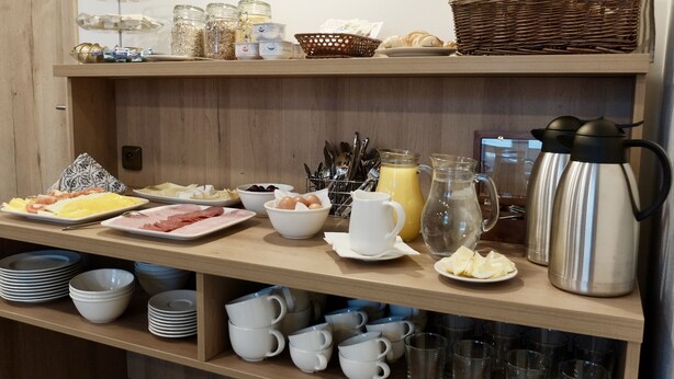 Un buffet de petit-déjeuner proposant une variété d’aliments, un coin café et un panier de pain.