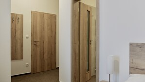 Une chambre d’hôtel avec une porte en bois, une table de chevet avec une lampe et un lit.