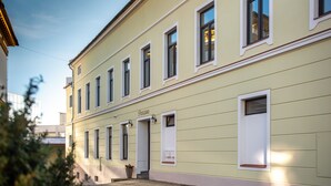 Un bâtiment à la façade plate, doté de nombreuses fenêtres et d’une porte portant l’inscription « Pension ».