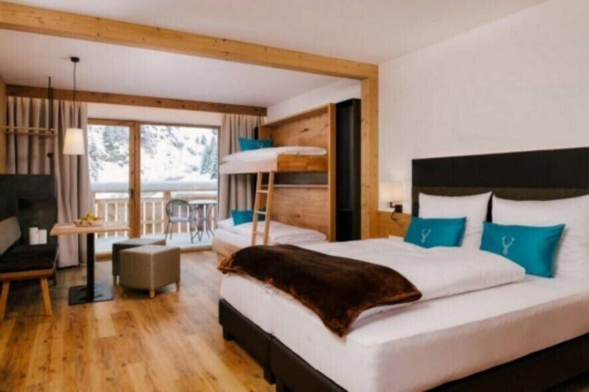 A bedroom with a bunk bed, a desk, a chair, and a TV.