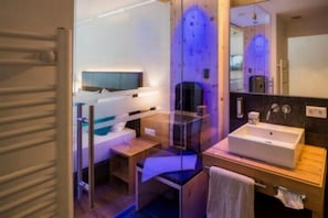 A modern bathroom with a glass shower enclosure, a wooden vanity, and a large mirror. - Bergresort Das JOCHELIUS (Nauders)