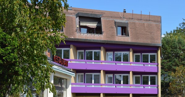 Un edificio de varios pisos con restaurante en la planta baja y hotel en los pisos superiores.
