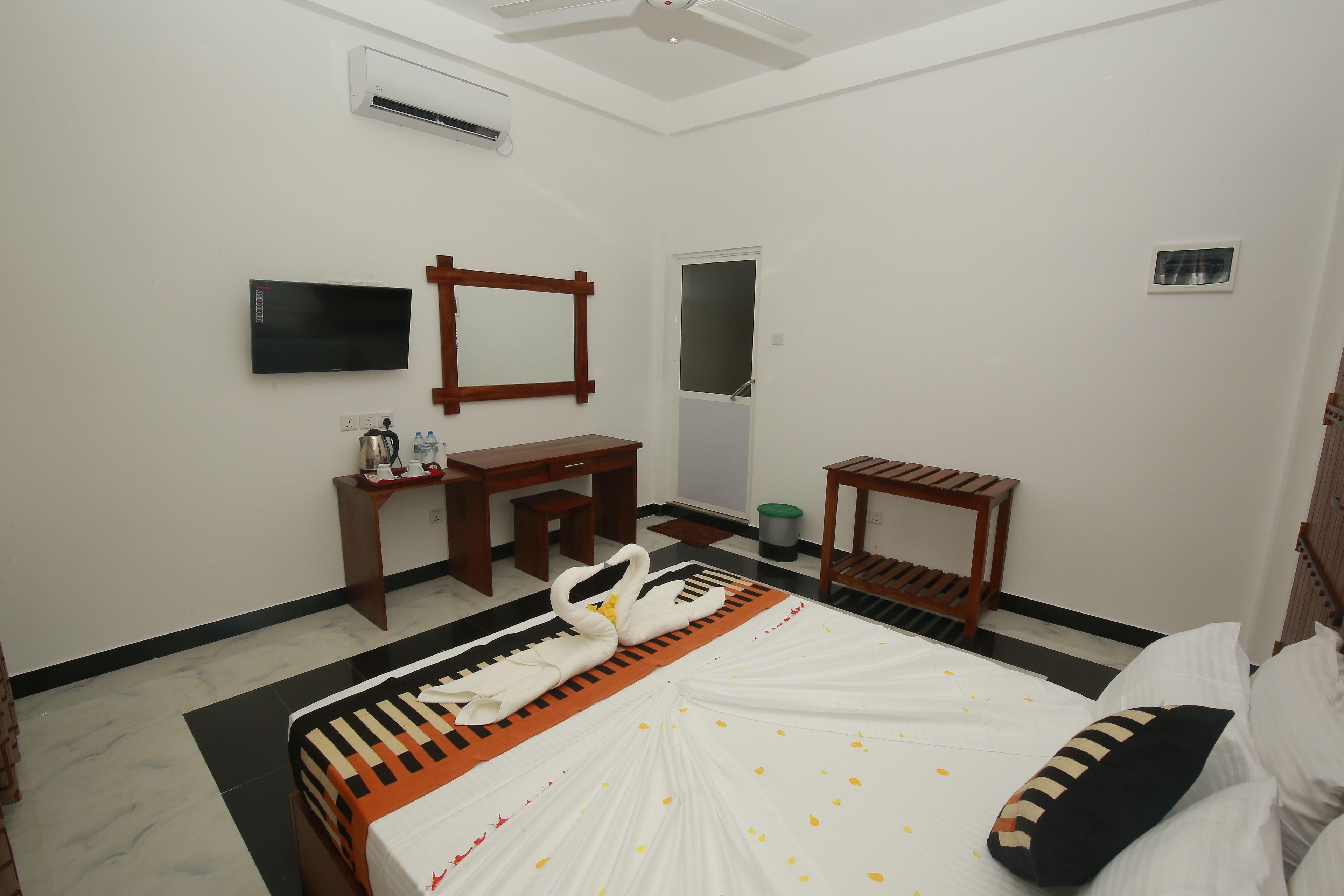 A hotel room with a bed, a desk, a chair, a TV, and a mirror.