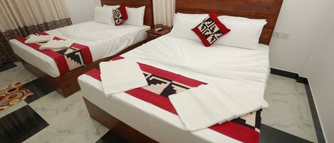 A hotel room with two beds, each with white bedding and red and black patterned pillows. The room has a checkered floor pattern and a wooden headboard.