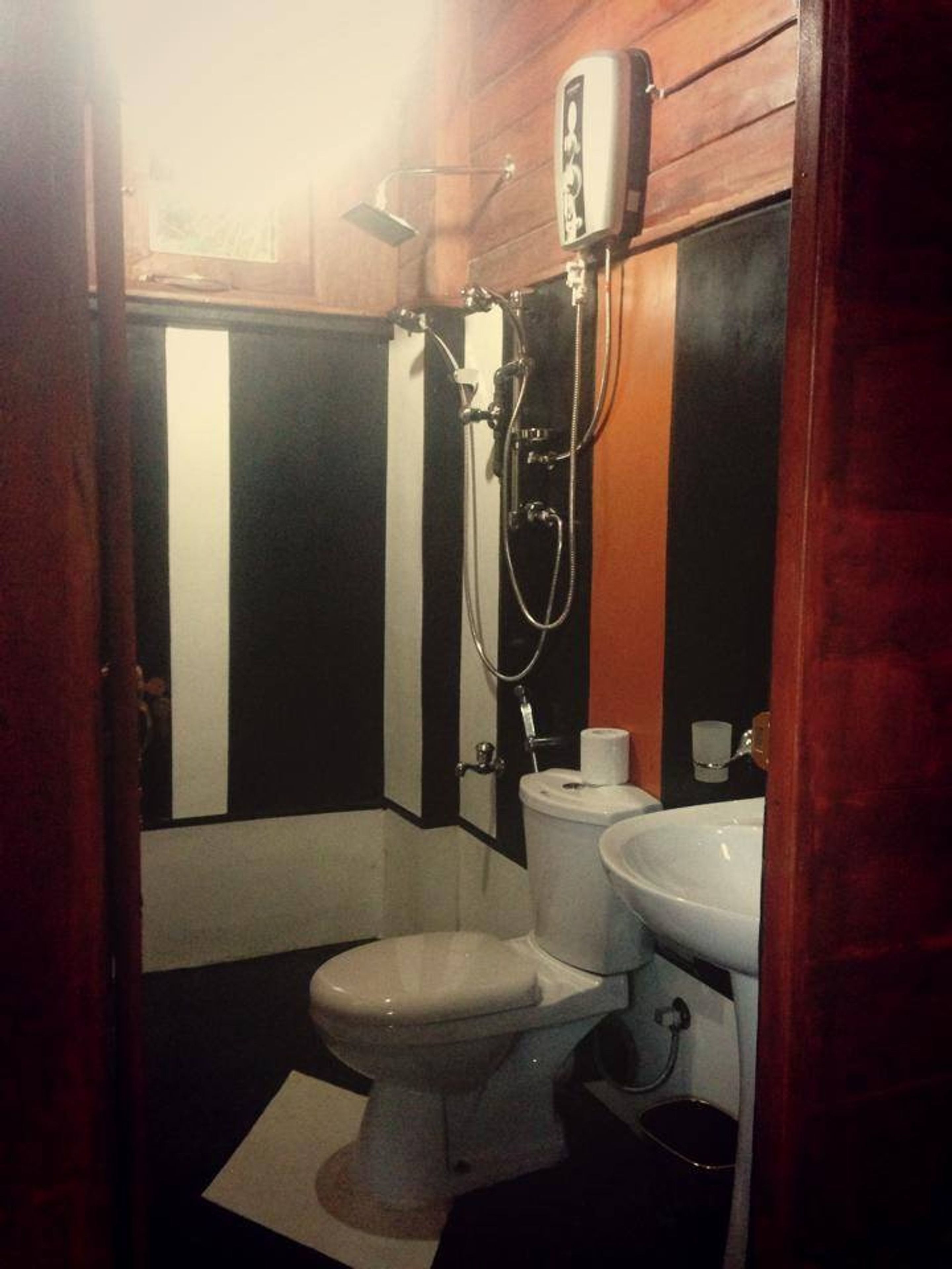 A compact bathroom with a toilet, sink, and shower.