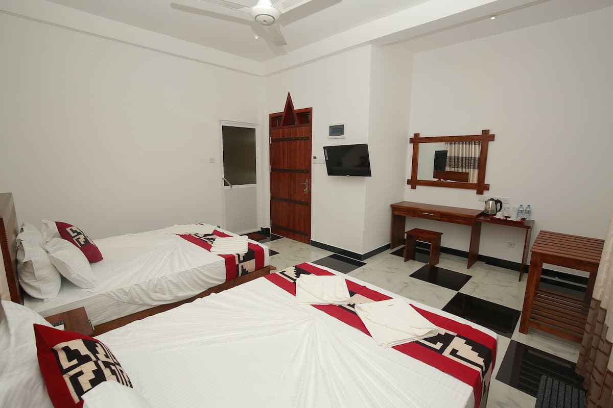 A hotel room with two beds, a desk, a chair, a television, and a mirror.