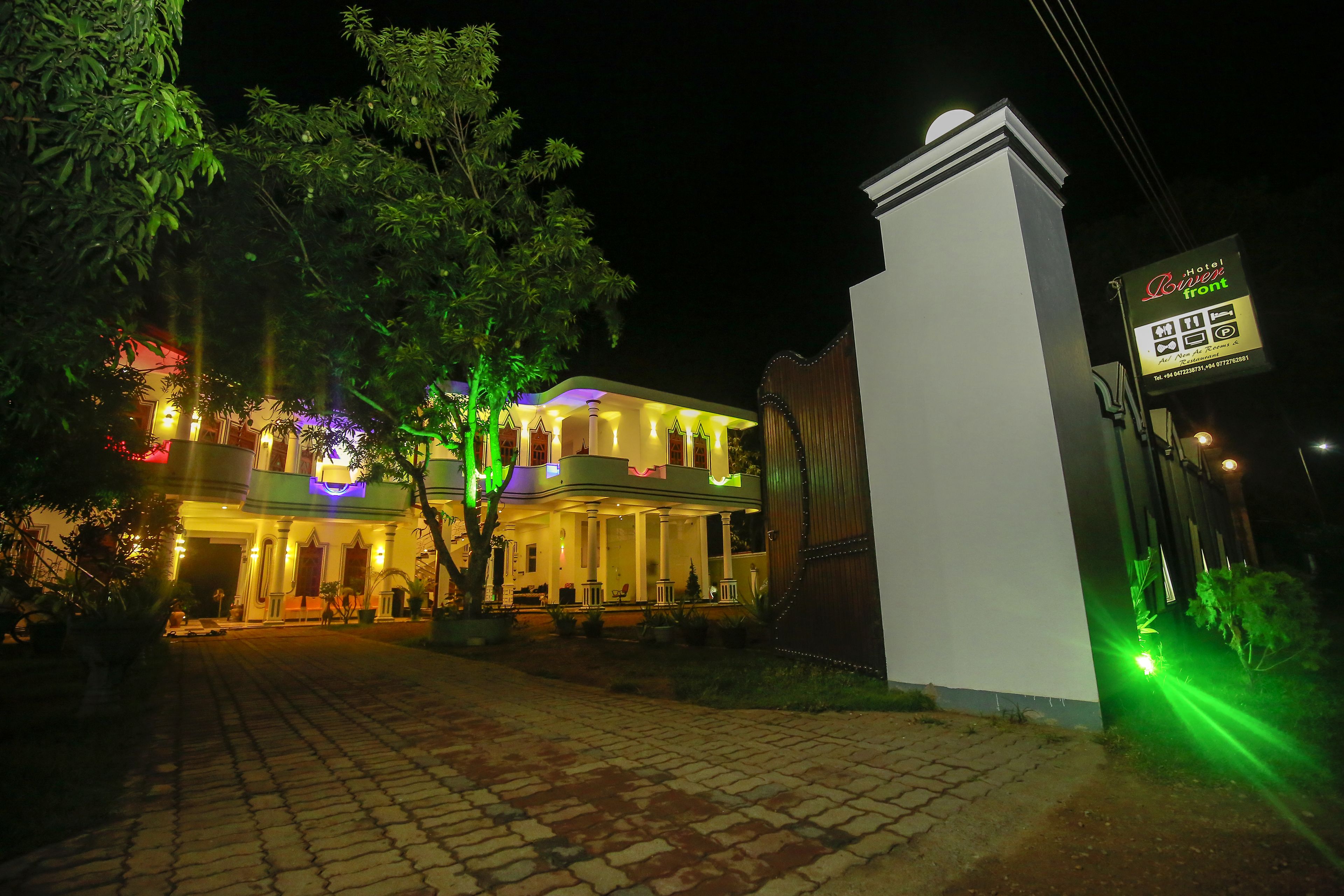 A hotel with a well-lit entrance, a covered outdoor area, and a signboard.